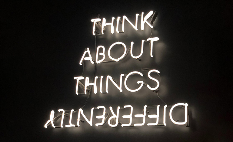 Neon sign with the words "Think about things differently"