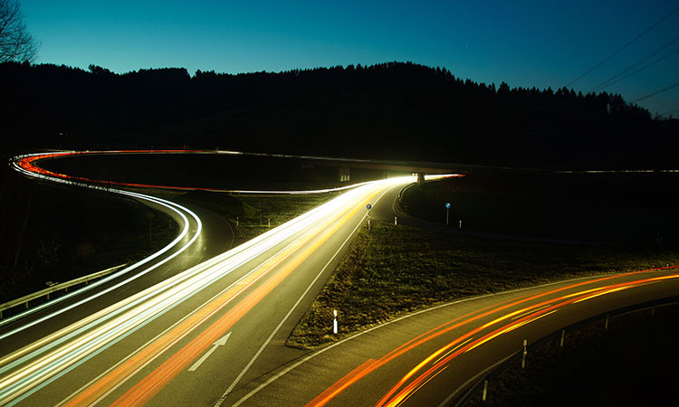 Intersecting highways at night with strands of yellow and orange light following the roads