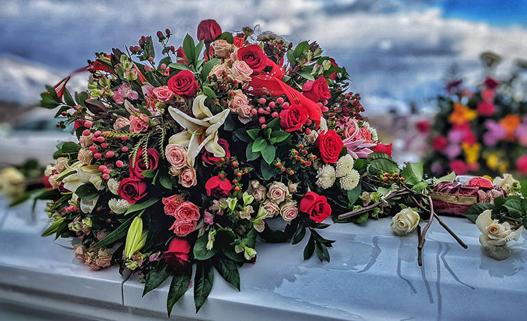 A coffin with a bouquet of roses on top