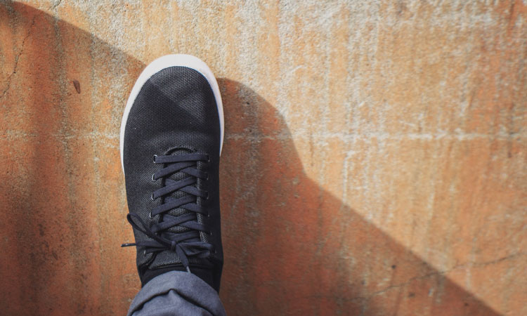 Foot in a black shoe on a brown road