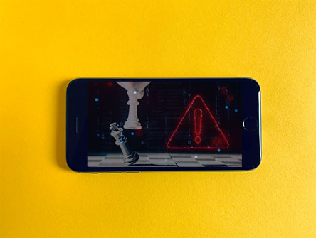 A smartphone with an image of chess and an alarm symbol.