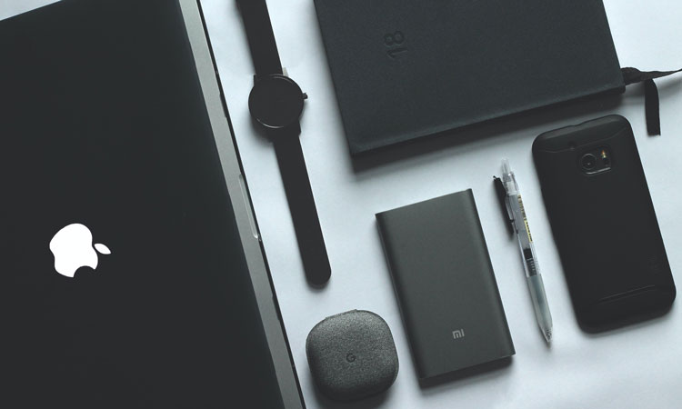 Black laptop , watch, notebook, smartphone, pen on a white surface