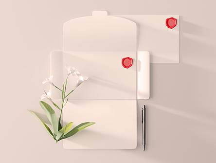 A blank letter open on a desk with a lily sitting next to it.