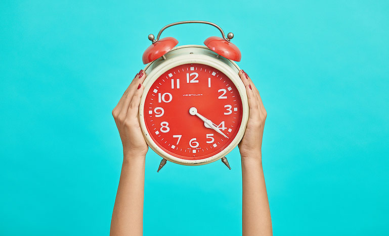 A person holding a vintage alarm clock