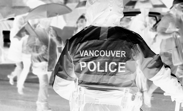 A Vancouver police officer standing in the rain.