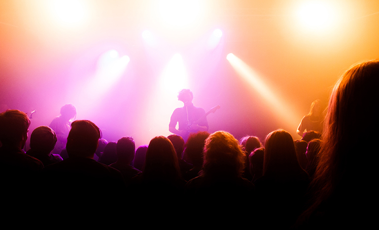 A band playing on stage with a large audience watching.