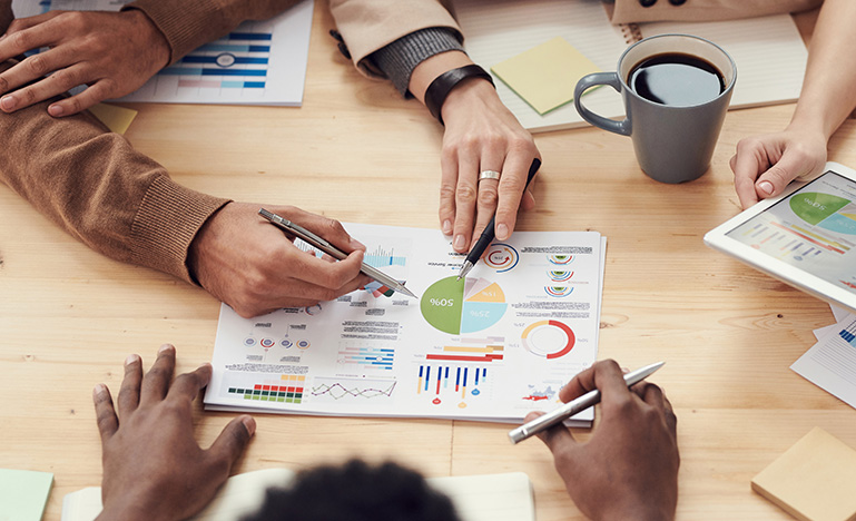 Four people examining graphs and statistics