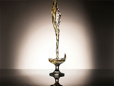 Golden liquid pouring into a glass goblet.