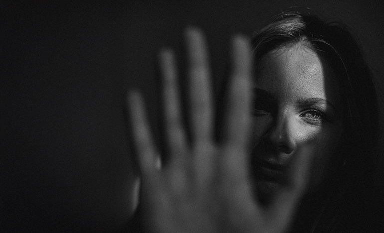 A woman in shadow holding up her hand, saying "stop".