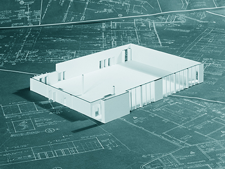 A model frame of a building sitting on a number of blueprints.