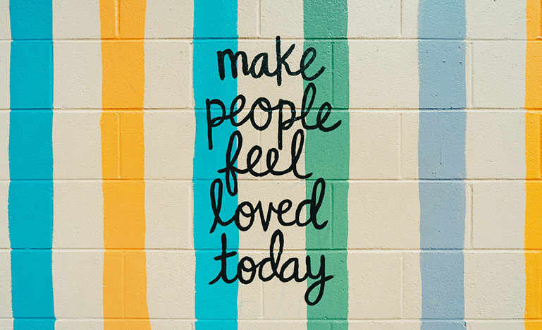 "Make people feel loved today" written on a concrete wall.
