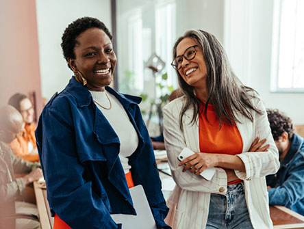 Two women standing next to each other, smiling. 