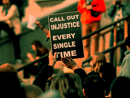 A protestor holding up a sign that reads "Call out injustice every single time"