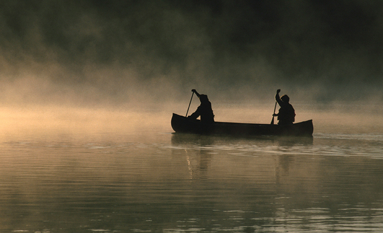 Two people paddling a canoe. 