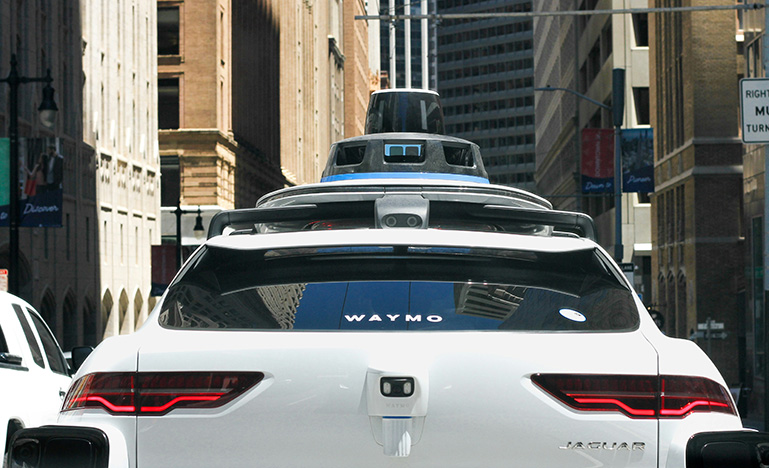 The back of a white, Waymo self-driving car