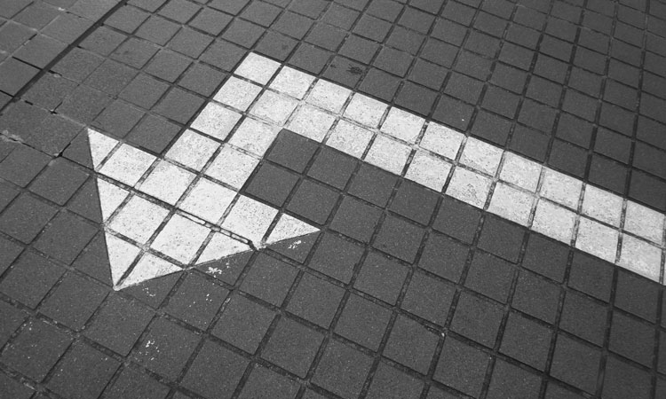 White arrow painted on a gray walkway