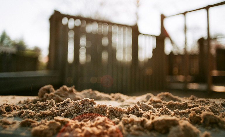 A sandbox with a blurred playground behind it