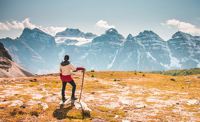 A person standing on top of a mountain looking out at a mountain range in the distance.
