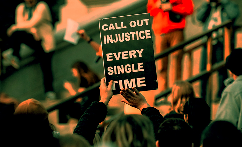 A protestor holding up a sign that reads "Call out injustice every single time"