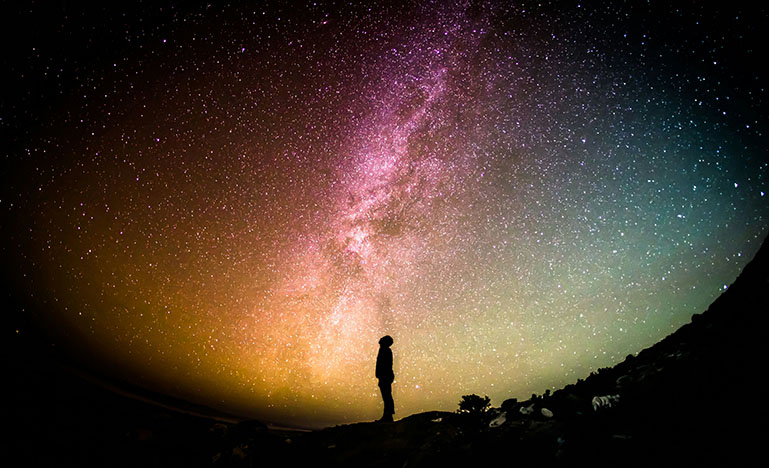 A person in shadow looking up at the night sky