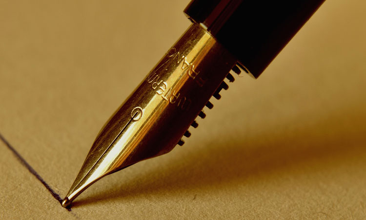 Fountain pen drawing a black line on a piece of yellow paper