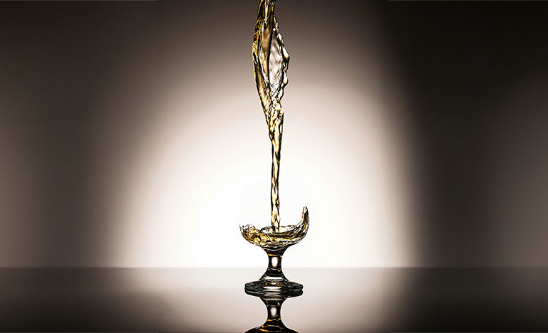 Golden liquid pouring into a glass goblet.