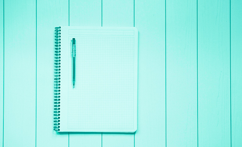 An open notebook and pen sitting on a table. 