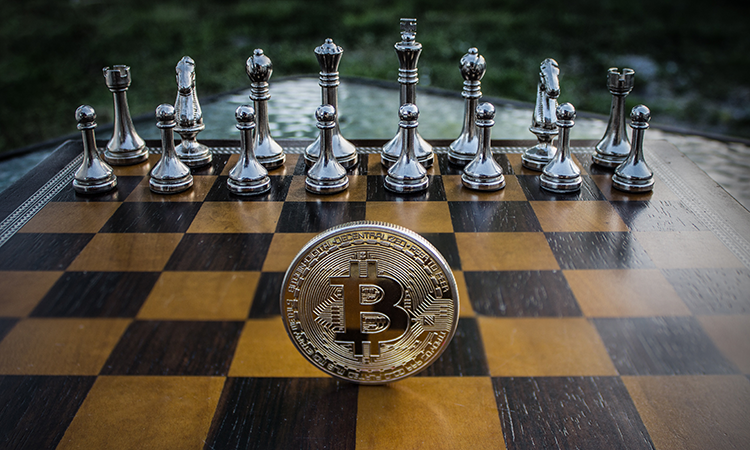 Silver chess set on a brown and black chessboard with a large silver bitcoin in front
