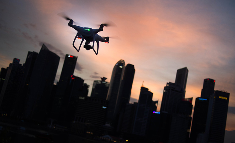 Drone flying in front of a skyline during a sunset