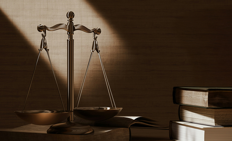 Scales of justice on desk surrounded by text books.