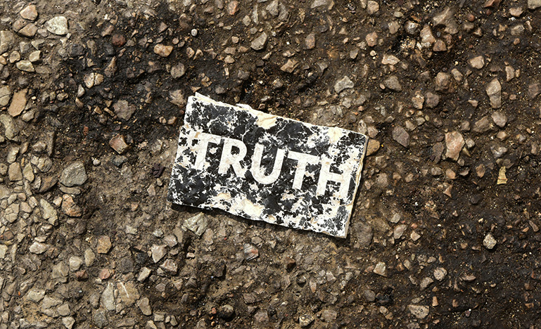 A damaged sign that reads "Truth" lying on the ground