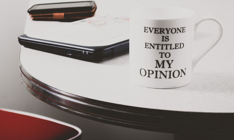 White mug on a table with the words "everyone is entitled to my opinion" on it 