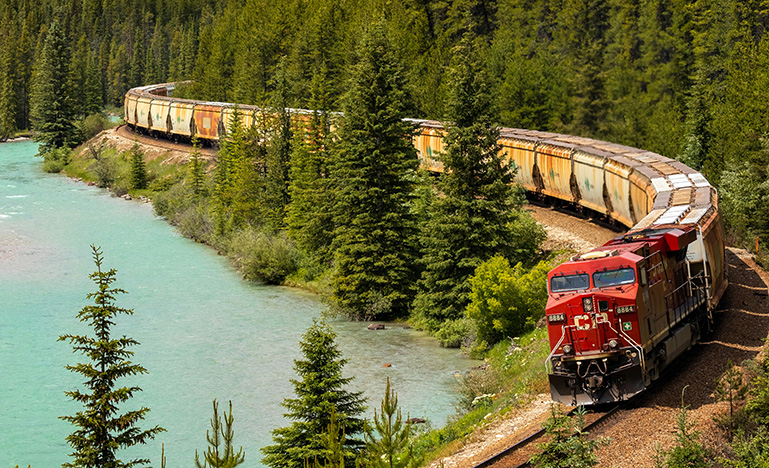 Train driving along a mountain beside a blue lake