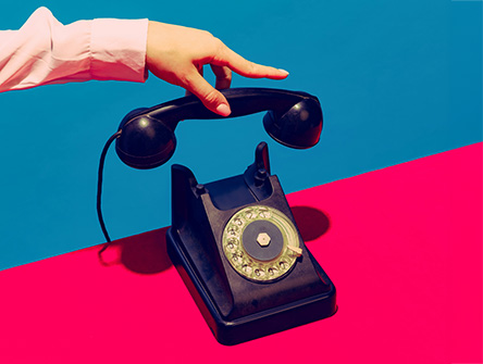 A hand holding the receiver of a vintage rotary phone. 