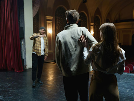 Three improv actors playing out a scene on stage.