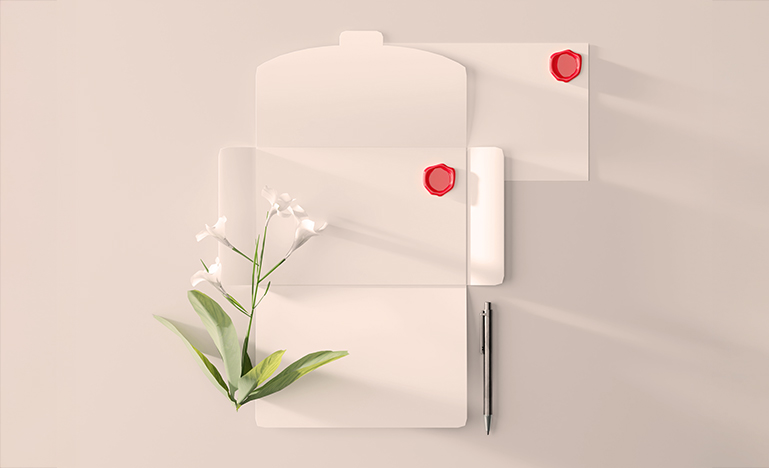 A blank letter open on a desk with a lily sitting next to it.