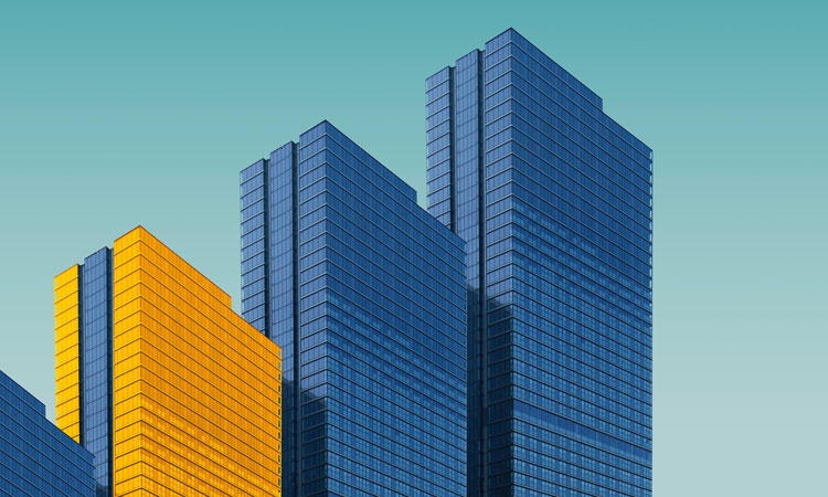 Two blue and one yellow skyscraper against a blue sky