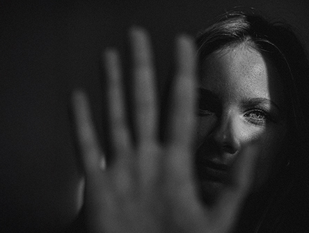A woman in shadow holding up her hand, saying "stop".